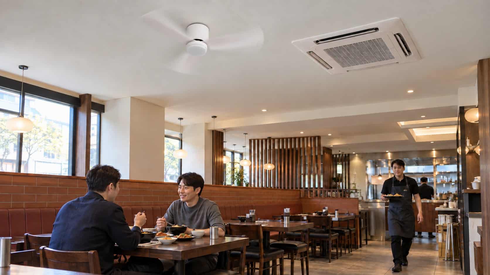 업소용 실링팬을 달면 뭐가 달라질까? 전기세부터 분위기까지 회전하는 흰색 실링팬과 천장형 시스템에어컨이 있는 식당에서 식사하는 손님과 홀 직원의 연출 이미지